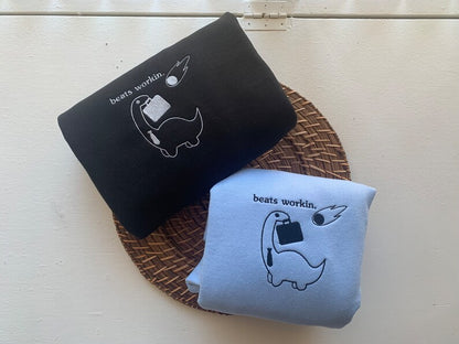 "Beats Workin" Dinosaur Embroidered Sweatshirt | Funny Minimalist Dino with Briefcase & Meteor | Dark Work Humor Gift for Adults