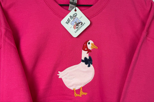 Pink t-shirt with a cartoon chicken design on a hanger
